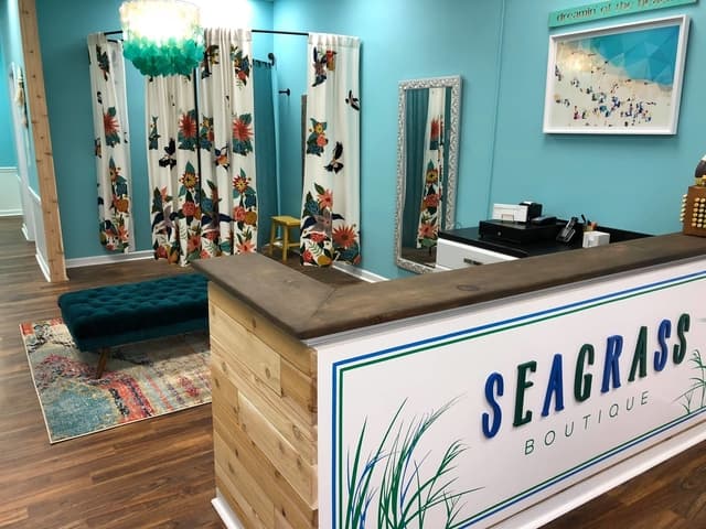 Inside Seagrass Boutique — turquoise walls, floral fitting room curtains, and the Seagrass sign
